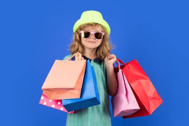 Child boy with shopping bags. Sale and discount concept. Kid in trendy hat and shirt shopping holding shopping bags