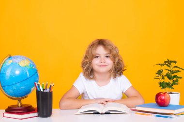 Okul çocuğu kitap okuyor. Okul ve eğitim kavramı. Sarı arka planda izole edilmiş şirin çocuk portresi. Okula geri dön.