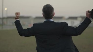 Heyecanlı başarılı iş adamı zafer jesti yapıyor. Mutlu başarılı iş adamları zaferi kutluyor. Başarılı iş adamı dışarıda gülümsüyor. Profesyonel başarılı iş adamı, kazanan..