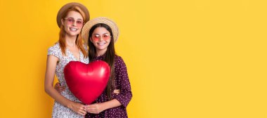 Anne ve kız çocuk afişi, kopyalama alanı, izole bir arka plan. Sarı arka planda aşk balonu tutan mutlu anne ve kız.