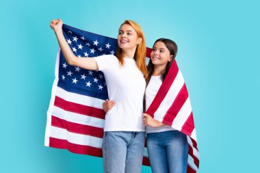 Vatansever bayram. Mutlu aile, mavi izole edilmiş stüdyo geçmişinde Amerikan bayrağı taşıyan anne ve kızı. ABD 4 Temmuz 'da bağımsızlığını kutladı