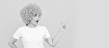 Parti eğlencesi peruğu. Şuraya bak. Şaşaalı parti bakışı. Palyaço peruklu ucube kadın parmakla gösterip, uzayı kopyalıyor. İzole edilmiş yüz portresi, kopyalama alanı olan pankart