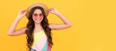 Yaz hasır şapkalı ve gözlüklü mutlu çocuk sarı arka planda kıvırcık saçlı, yaz tatilinde. Çocuk yüzü, yatay poster, izole edilmiş genç kız portresi, fotokopi alanı olan pankart