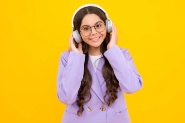 Teen girl in headphones listen to music. Wireless headset device accessory. Child enjoys the music in earphones on yellow background