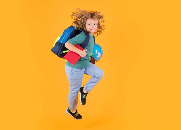 Full length body of cheerful school child jumping running back to school isolated over yellow background