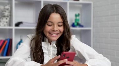 Neşeli öğrenci kız sohbet ediyor sınıfta akıllı telefon kullanıyor, modern hayat..