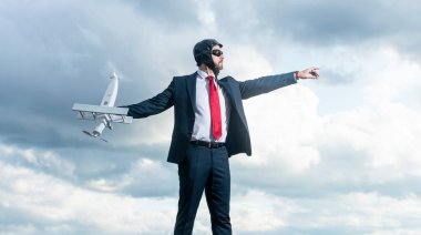 Rüya gören takım elbiseli iş adamı ve pilot şapkalı uçak fırlatma oyuncağı..