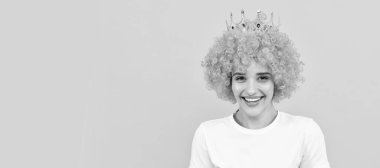 Kıvırcık palyaço peruğu ve kraliçe tacıyla parti için mutlu, bencil kadın, mutluluk. İzole edilmiş yüz portresi, kopyalama alanı olan pankart