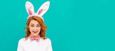 Tavşan kulaklı ve mavi arka planda papyonlu bir Paskalya kadını şaşırttı. İzole edilmiş yüz portresi, kopyalama alanı oluşturulmuş pankart