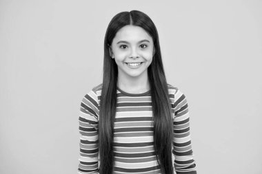 Stüdyonun arka planında izole edilmiş genç bir kızın portresi. Çocukluk yaşam tarzı konsepti. Kopyalama alanı oluşturun. Mutlu yüz, pozitif ve gülümseyen genç kız duyguları