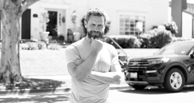 Karizma dolu. pozitif duygular. Gülümseyen sakallı adam başarıyı kutluyor. Yakışıklı, olgun bir adam ellerini çaprazladı. Açık havada başarılı bir erkek model. erkek modası.