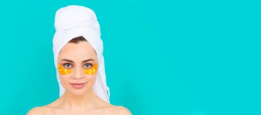 Göz bantları, göz altı bantları. Kızın yüzünde havluyla kolajen altın göz bantları var. Güzel kadın, izole edilmiş yüz portresi, taklit alanı olan pankart.