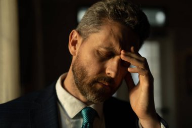 Baş ağrısı, yorgunluk ve stres. Takım elbiseli bir iş adamı dizüstü bilgisayar kullanıyor, migreni tuttu. Baş ağrısı konsepti. Ofiste acılı adamlar streslidir. Stresli ve baş ağrısı