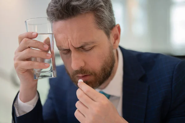 stock image Stressed business man having headache at office. Tired businessman is working overtime and has headache. Man taking a Medicine pill from headache migraine