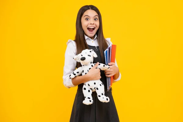 stock image Back to school. Teenager schoolgirl hold book with toy ready to learn. School children on isolated yellow studio background. Excited face, cheerful emotions of teenager girl