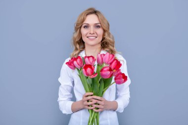 Gri arka planda bahar lale çiçekleri olan mutlu sarışın kadın..