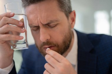 Yorgun, baş ağrısı ve dizüstü bilgisayardan dolayı göz yorgunluğu. Stres, yorgunluk ve göz yorgunluğu olan bir iş adamı. Adam baş ağrısından ilaç alıyor.