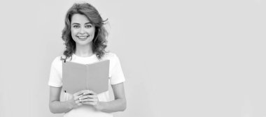 Kitaplı öğrenci ya da bayan öğretmen. Neşeli kadın sarı arka plan, okul hakkında kitap tutuyor. İzole edilmiş yüz portresi, kopyalama alanı olan pankart