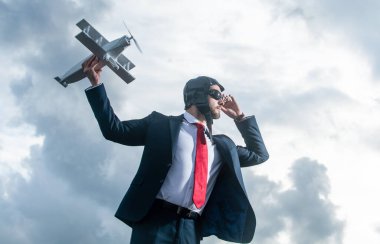 Takım elbiseli ve pilot şapkalı iş adamı uçan uçak oyuncağını fırlattı.