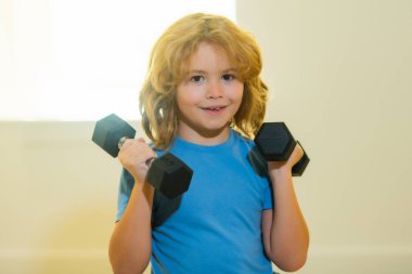 Beden eğitiminde çocuk çalıştıran çocuk. Çocuk dambıllarla çalışıyor. Spor ve çocuk eğitimi.