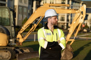 Worker with bulldozer on site construction. Man excavator worker. Construction driver worker with excavator on the background. Construction worker with tractor or construction vehicle at building