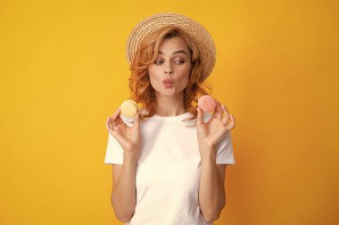 Çekici bir kadın lezzetli bir badem kurabiyesini ısırmak istiyor. Makarnayı ağzının kenarında tutuyor. Güzellik kızı tatlıdan hoşlanıyor.