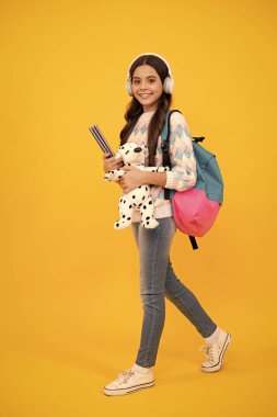 Funny school girl with toy isolated on yellow background. Happy childhood and kids education