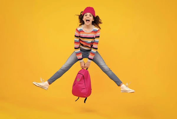 stock image Amazed teenager. Winter school. Teenager school girl with backpack in autumn clothes on yellow isolated studio background. Crazy jump and run, jumping kids. Excited teen girl