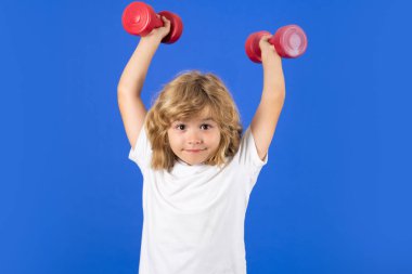 Çocuklarla boş zamanlarında spor aktiviteleri. Dambıl tutan sarışın çocuk. Çocuklar için spor egzersizleri. Halterleri kaldıran komik çocuk.