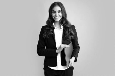 Portrait of a cheerful young casual girl standing isolated over gray background, using laptop computer. Business woman at work