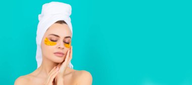 Genç bayanın yüzünde havluyla kolajen altın göz bantları var. Güzel kadın, izole edilmiş yüz portresi, taklit alanı olan pankart.