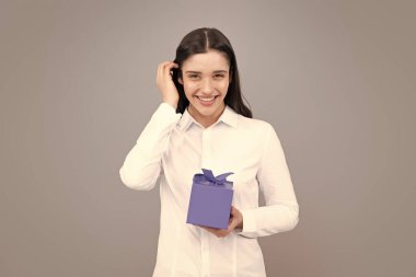 Şu anki kutusuyla çekici bir kadın gri arka planda şaşırmış yüz ifadesiyle poz veriyor. Kız elinde kurdeleyle süslenmiş bir hediye tutuyor. Sevgililer günü, doğum günü, mutlu yıllar hediye insanlar konsepti