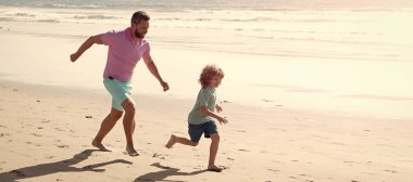 Baba ve oğul yaz plajında açık havada koşuyor. Kopya alanı, çocukluk ve ebeveynlik ile afiş asıyor. Baba ve oğul yaz plajında koşuyor. Aile seyahati ve tatil.