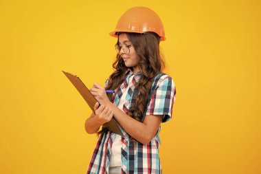 Teenager child painter in helmet with clipboard. Child in hard hat. Kid engineer on construction site. Renovation and repair