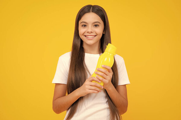 Teen girl with water from plastic bottle on isolated background, copy space. Kid girl care body hydration. Active leisure and water balance. Happy teenager portrait. Smiling girl