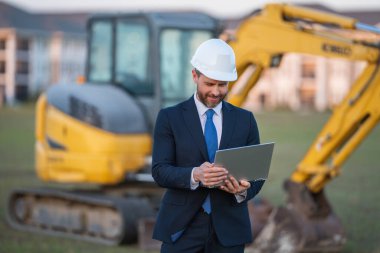 Kazıcının yanında inşaat işçisi. Evin önünde kendine güvenen bir inşaat sahibi. Mimar, inşaat mühendisi. İnşaat alanında güvenlik yeleği ve kasketi olan bir inşaat sahibi.