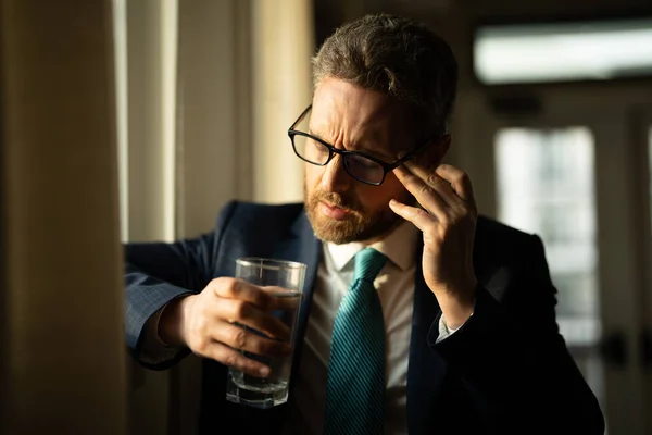 stock image Man taking a Medicine pill from headache migraine. Tired bored business man has office syndrome. Exhausted man with migraine or headache. Office worker, manager or freelancer having a headache