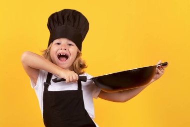 Tavalı küçük bir aşçı. Aşçı üniformalı küçük bir çocuğun portresi. Şef çocuk stüdyo arka planında izole edilmiş. Aşçı olmak için sevimli bir çocuk. Aşçı şapkası giymiş bir çocuk.