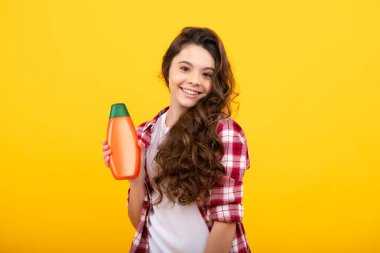 Şampuan kremi kullanan bir çocuk. Günlük kozmetik bakım. 12, 13, 14 yaşlarındaki ergen çocuğun elinde saç ve cilt bakımı şişesi var. Güzellik sağlığı ve kozmetik ürünleri. Mutlu genç