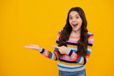 Teenager child pointing to the side with a finger to present a product or idea. Teen girl in casual outfit pointing empty space. Amazed teenager. Excited teen girl