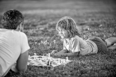 fatherhood and childhood. checkmate. spending time together. strategic and tactic. tutorship. dad and kid play logic game. father and son playing chess on grass. fathers day. happy family closeup.