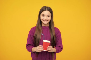 Teenage girl with take away cup of cappuccino coffee or tea. Child with takeaway cup on yellow background, morning drink beverage