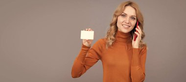 Cep telefonunda konuşan mutlu kadın fotokopi alanı gri arka planı ve bankacılık için kredi kartı gösteriyor. Kadın portresi, kopyalanmış başlık pankartı