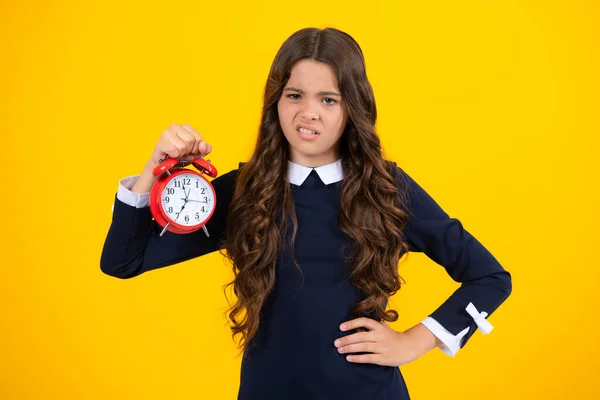 stock image Portrait of teenage girl with clock alrm, time and deadline. Studio shot isolated on yellow background. Angry teenager girl, upset and unhappy negative emotion