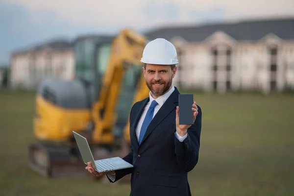 Worker in suit and helmet. Investor civil engineer, construction manager. Construction building developer at a construction site. Successful architect. Handsome hispanic builder man in suit