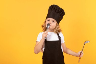 Cooking, culinary and kids. Little boy in chefs hat and apron on studio isolated background