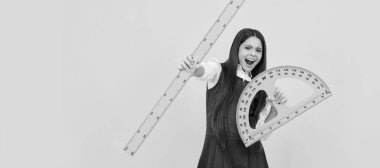 emotional child hold math protractor and ruler in school on yellow background. Portrait of schoolgirl student, studio banner header. School child face, copyspace