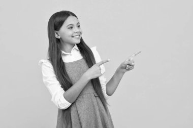 Genç bir çocuk bir ürün ya da fikir sunmak için bir parmağıyla kenarı işaret ediyor. Boş bir yeri işaret eden günlük kıyafetli bir genç kız. Mutlu kız yüzü, pozitif ve gülümseyen duygular