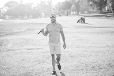 Adam üstüne adam yeşil çimlerde yürüyor. Yaz etkinliği. Profesyonel açık hava sporu. Profesyonel golf sahasında erkek golfçü. Golf sopasıyla şapkalı golfçünün portresi. insan yaşam tarzı.