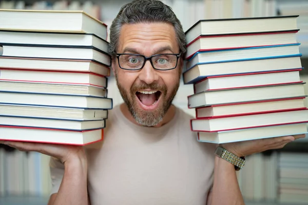 Funny teacher hold many books. Crazy teacher with books. Excited teacher in school book library. University exam. Study teach in college. Educator learning courses. Studying literature